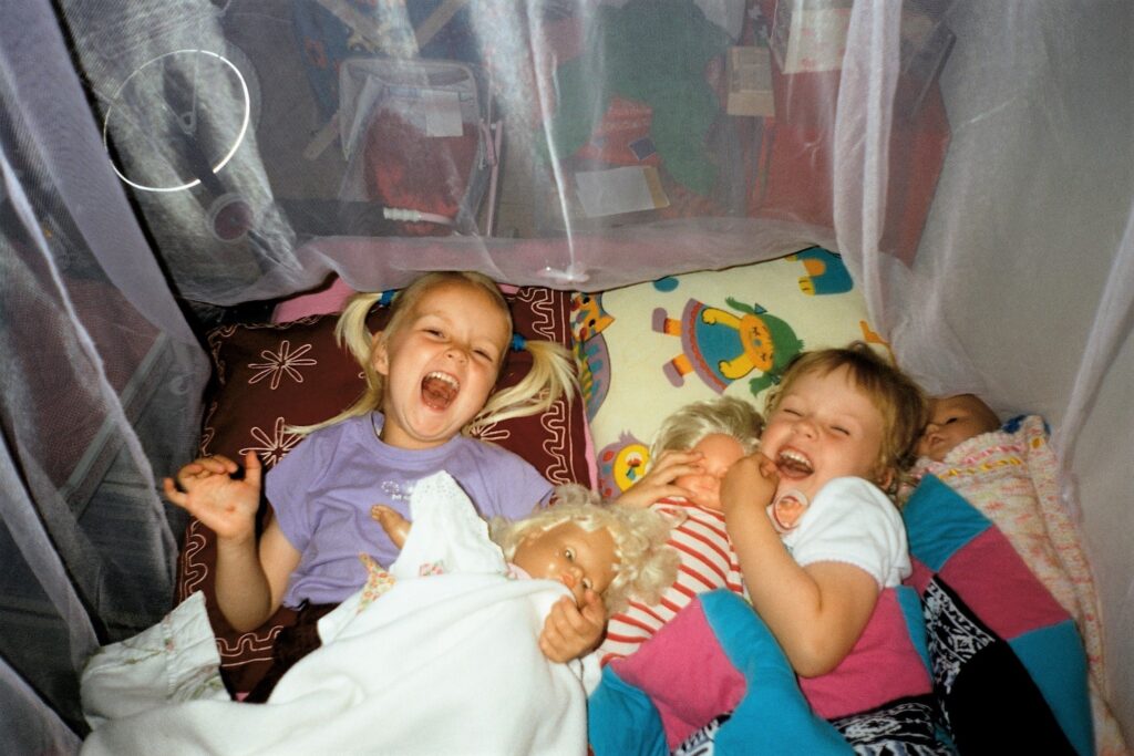 To piger der griner i et telt med dukker i hænderne